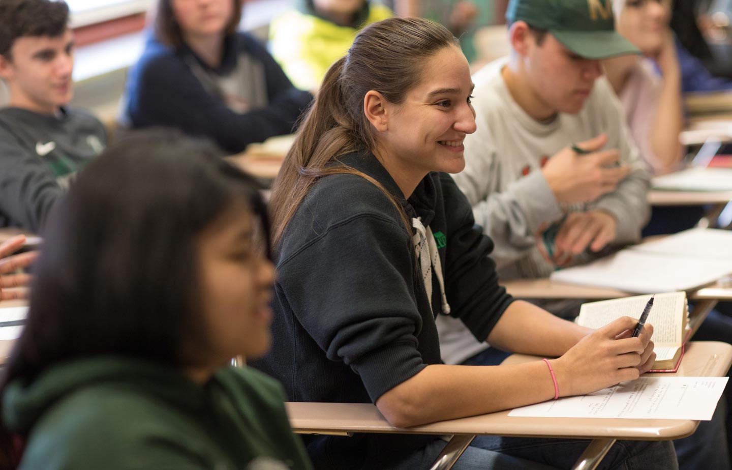 Smiling high school woman sitting at a desk in a classroom