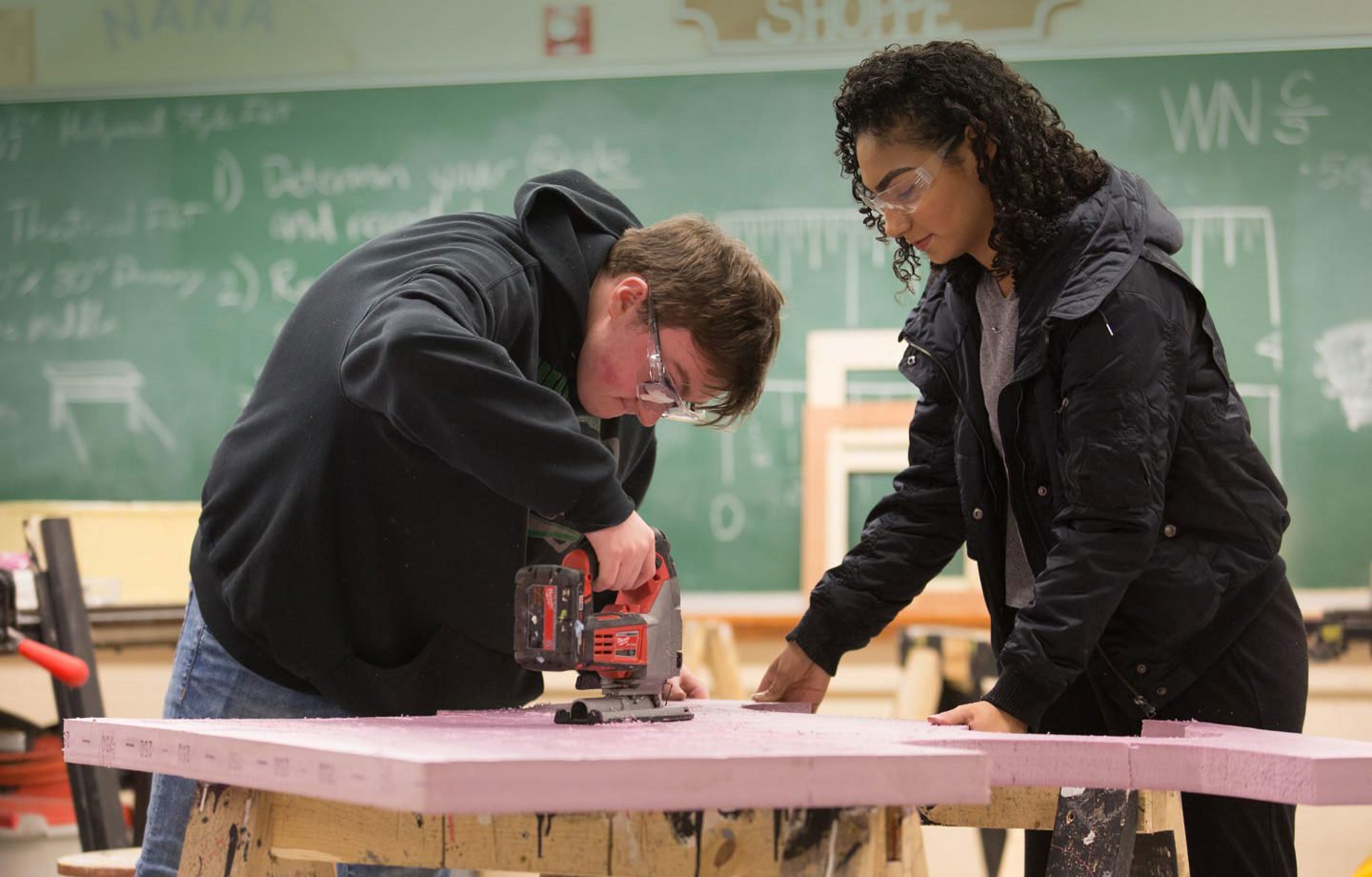 A male and female high school student working together in a wood shop